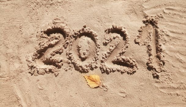 The concept of a New year. Heart and numbers 2021 in the sand. Summer beach holidays . The message is handwritten