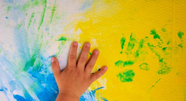 Children's hands on watercolors.Cardboard stained with watercolor paint.Classes with children.
