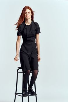 woman high chair indoors full length black dress red hair model boots. High quality photo