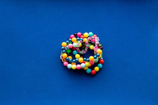 Eight multi-colored bracelets arranged in a flower shape on a blue background. Bracelet with beads.