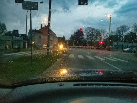 Closed barriers of a railroadcrossing at dusk in the rain