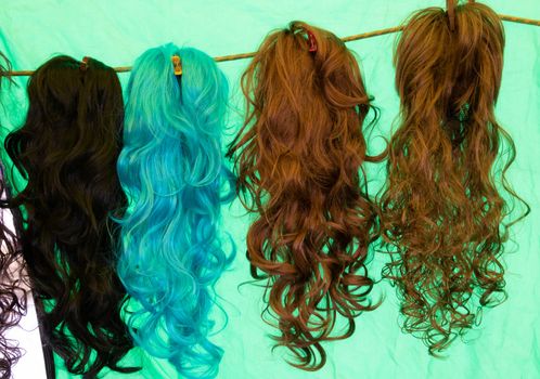 Coloured wigs with long wavy fake hair hanging next to each other