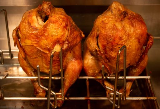 two carcasses of grilled chickens sit behind the glass of the window. market