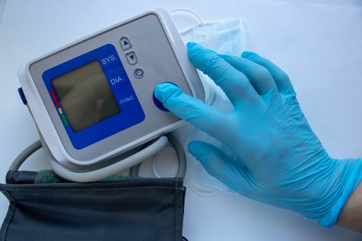 Male hands wear glove press start button on blood-pressure meter isolated on white background.