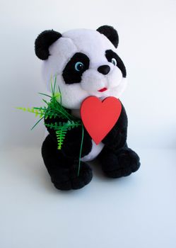 Soft plush Panda toy with a red wooden heart on a white background.Concept gift for Mother's day, Valentine's day, March 8