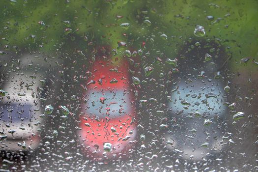 Raindrops on the window, with cars in the Parking lot in the background.