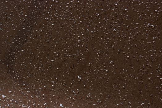 water drops on a brown metal surface, top view, for background. rain drips on the surface.