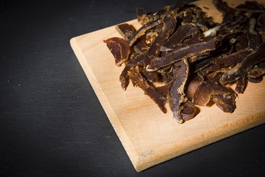 Dried beef sliced on a wooden cutting board