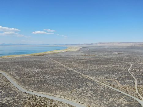 Aerial view of dusty dry desert land with Mono Lake on the background, Mono County, California, USA