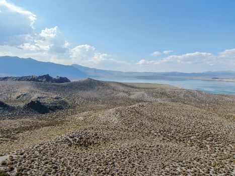 Aerial view of dusty dry desert land with Mono Lake on the background, Mono County, California, USA