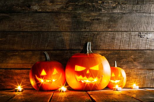 Halloween pumpkin head lanterns and burning candles on wooden background