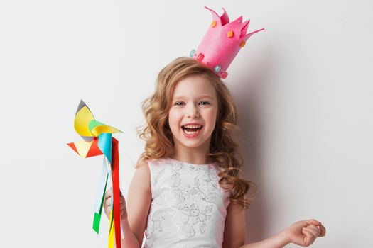 Beautiful little candy princess girl in crown holding pinwheel and smiling