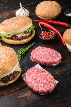 Burgers and the fresh ingredients on dark wooden background.