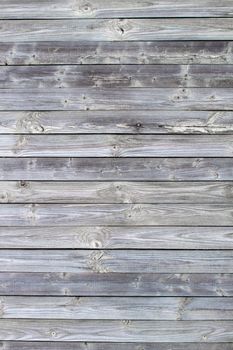 Wooden background made of old boards. The texture of an old rustic wooden fence made of flat processed boards. Wooden fence made of old boards with the inclusion of Knots. Background design