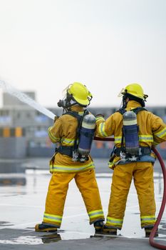 Firefighter or fireman team work water spray by high pressure nozzle to fire.