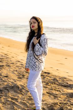 A beautiful Asian model in white fancy fit tops and stylish cotton lycra stretchable trouser and blurred background of Indian beach bech