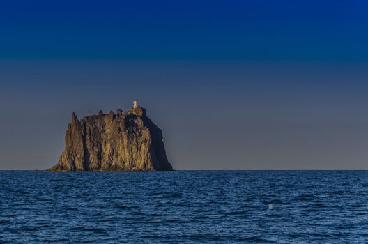 Emerging rock of the Tyrrhenian Sea with its lighthouse called strombolicchio in front of the island of stromboli Aeolian islands italy