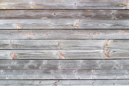 Wooden background made of old boards. The texture of an old rustic wooden fence made of flat processed boards. Wooden fence made of old boards with the inclusion of Knots. Background design