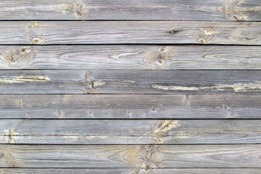 Wooden background made of old boards. The texture of an old rustic wooden fence made of flat processed boards. Wooden fence made of old boards with the inclusion of Knots. Background design