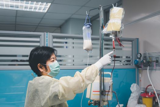 Doctor check saline intravenous at C-line or A-line on patient flu covid19 asian elder woman 70s on patient bed in intensive care unit (ICU.) room at hospital in concept illness, healthcare in life