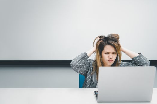 Asian woman is student,businesswoman working by computer notebook, laptop in office meeting room with whiteboard background with annoyed, displeased emotion in concept working woman,unhappy in life