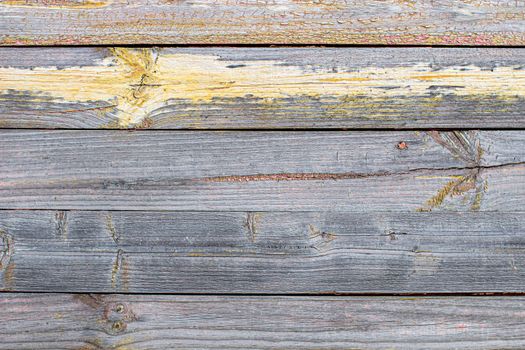 Wooden background made of old boards. The texture of an old rustic wooden fence made of flat processed boards. Wooden fence made of old boards with the inclusion of Knots. Background design