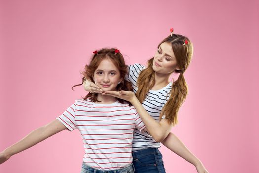 Cheerful mom and daughter lifestyle joy striped shirts family pink background. High quality photo