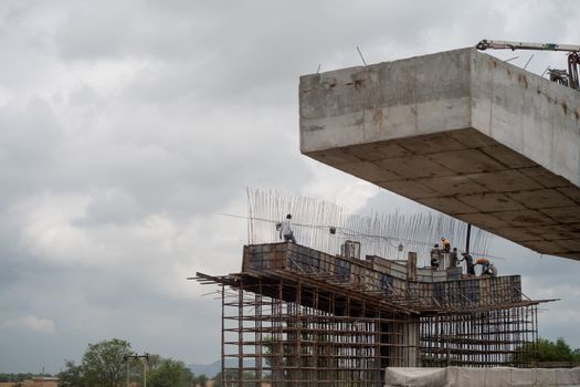 Gurgaon, Delhi - circa 2020 : Labor and workers standing on a support for a bridge under construction with rebar support frame visible. Shows the rapid development and growth of infrastructure projects across the country