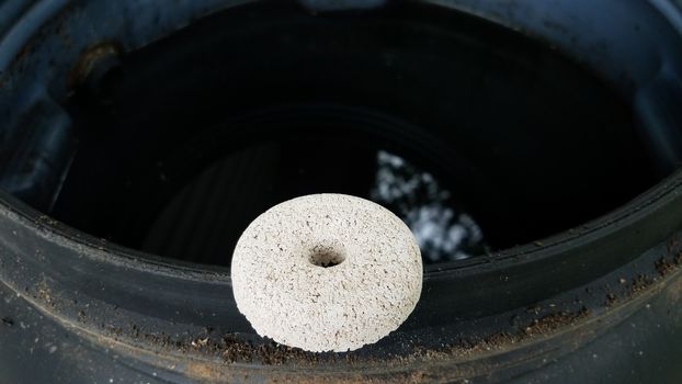 circular white mosquito tablet insecticide on edge of rain barrel with water