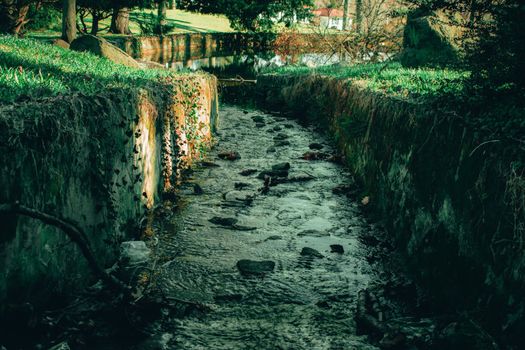 A Man Made Stream With Cobblestone Walls Flowing Into a Lake at Elkins Estate