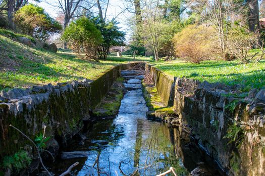 A Man Made Stream With Cobblestone Walls Flowing Into a Lake at Elkins Estate