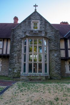 A Large Arched Window With a Cross on the Roof in an Old Cobblestone Building