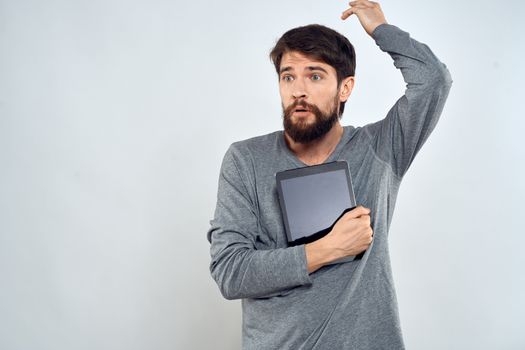 emotional man holding tablet technology communication internet work light background. High quality photo