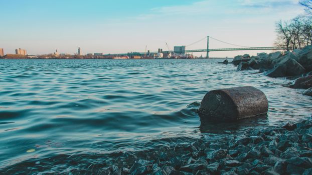 A Log on the Shore of the Deleware River at Penn Treaty Park With the Ben Franklin Bridge Behind It