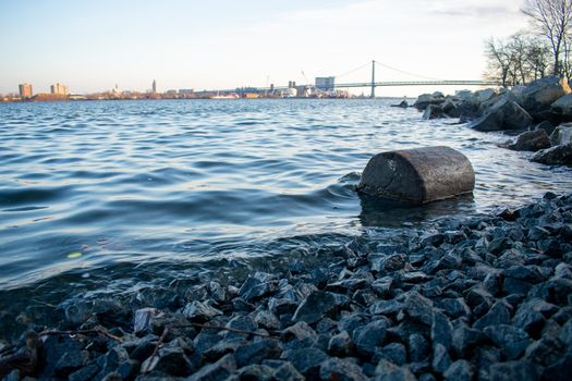 A Log on the Shore of the Deleware River at Penn Treaty Park With the Ben Franklin Bridge Behind It