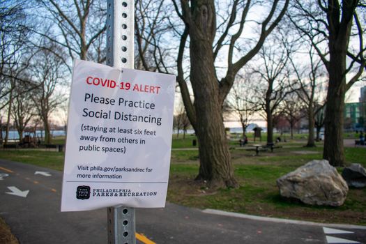 PHILADELPHIA, PENNSYLVANIA - MARCH 26, 2020: A Sign from Philadelphia Parks and Recreation at the Penn Treaty Park States a COVID-19 Alert and Asks Park-Goers to Practice Social Distancing