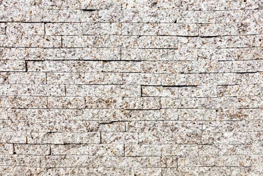 Wall background and texture with gray granite stripes with beige spots, close-up.