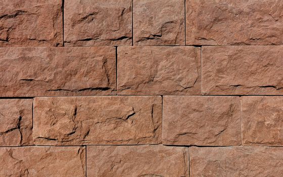 Wall background and texture of brown granite tiles with chips around the perimeter, close-up.
