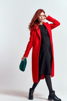 emotional woman in a red coat and with a hat in full growth on a light background black boots pose model. High quality photo
