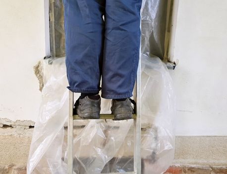 Closeup of worker´s legs on the ladder during house reconstruction.