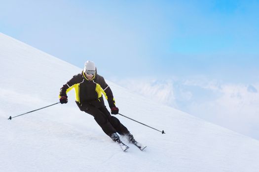 Alpine skier on piste running downhill in beautiful Alpine landscape. Blue sky on background. Free copy space for text