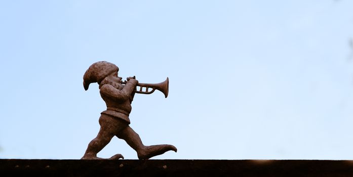 dwarf playing a trumpet in front of blue sky