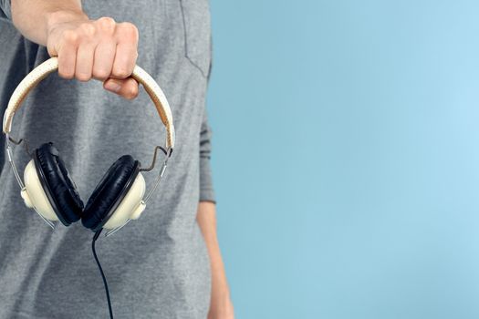 Headphones in man hands cropped view music technology blue background. High quality photo
