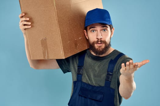 A man in working uniform with boxes in the hands of a carriage delivery service blue background. High quality photo