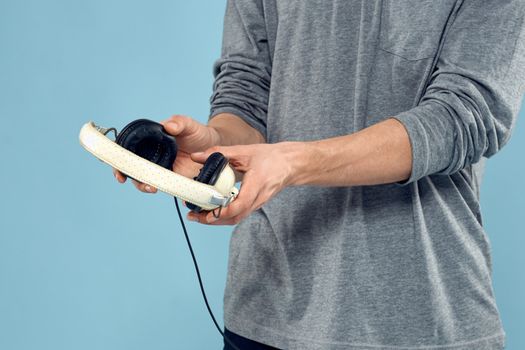 Headphones in man hands cropped view music technology blue background. High quality photo