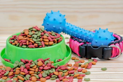 Pet food with rubber toy on wooden background