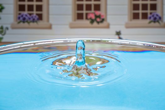 Abstract photo of a pool with water on the backgrounds of a house. Splash of water close up.A frozen drop of water is photographed at high speed.The slow dripping of the liquid with the air bubbles.