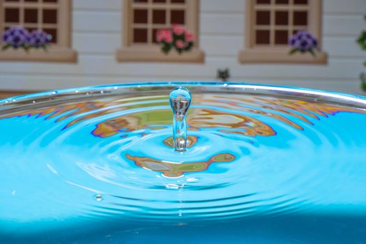 Abstract photo of a pool with water on the backgrounds of a house. Splash of water close up.A frozen drop of water is photographed at high speed.The slow dripping of the liquid with the air bubbles.