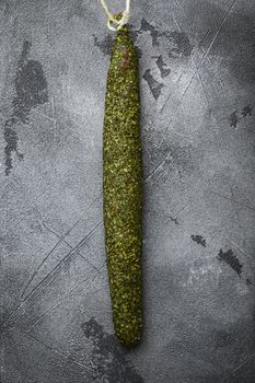 Spanish dry salami sausage fuet in herbs on grey background, topview.