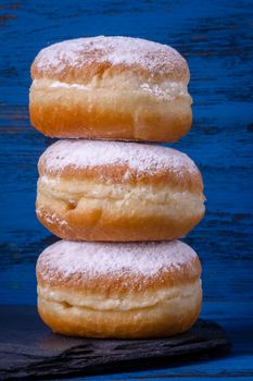 Berliner jelly filled doughnut with raspberry and redcurrant on wooden background.